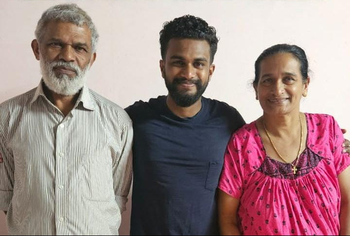 Three people standing together against a plain background